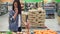 Attractive girl happy customer is choosing fruit in supermarket buying bananas, apples and oranges and putting them in