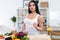 Attractive girl holding glass of milk, having healthy snack while preparing vegetable dish. Beautiful fit female cooking