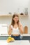 Attractive girl holding vitamin D or omega3 capsule and white jar mockup in kitchen. Food active additives.