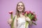 Attractive girl holds a bouquet of flowers on a pink background and gives one tulip, the seller offers flowers, a woman gives