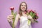 Attractive girl holds a bouquet of flowers on a pink background and gives one tulip, the seller offers flowers, a woman gives