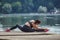 Attractive girl in a mask and sportswear is doing gymnastic exercises on a wooden pier in a city park. safe outdoor workout