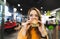 Attractive girl in orange clothes and glasses sits in a fast-food restaurant and eats a great appetizing burger