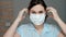 Attractive girl puts on surgical mask on her face. Cold, flu, virus, acute respiratory infections, quarantine, epidemic, irony,