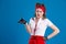 An attractive girl with a red bandana on her head holds a bottle of perfume with a surprised look on her face.