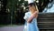 Attractive girl in silver and blue dress stands on stairs with stone balustrade near lion statue posing with arms across