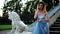 Attractive girl in silver and blue dress stands on stairs with stone balustrade near lion statue posing and talking