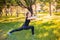 An attractive girl in a sports uniform makes a lunge exercise to stretch the muscles of the legs with dumbbells in her hands.