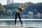 Attractive girl in sportswear does gymnastic exercises on a wooden pier in a city park