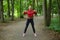 Attractive girl in sportswear is doing gymnastic exercises on the track in the forest park