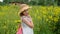 Attractive girl in summer hat posing on sunflowers meadow in village. Beautiful teenager girl standing on flowering