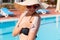 Attractive girl in sunhat applying sunscreen on shoulder by the pool. Sun Protection Factor in vacation, concept