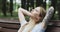 Attractive girl with a tattoo on her hand sits on a bench and looks at the sky.