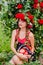 Attractive girl with a wreath of red roses with a basket of vegetables: tomatoes, eggplants, peppers