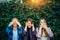 Attractive girls fool around and laugh on a summer day in the park. Three women cover their ears, eyes, and mouth