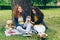 Attractive girls sitting on lawn in park with cute dog talking having fun