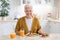 Attractive grandmother having lunch in kitchen alone