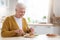 Attractive grandmother having lunch in kitchen alone