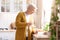 Attractive grandmother pouring water in kitchen at home