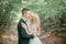 Attractive groom in green suit kisses tender bride`s cheek