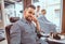 Attractive groomed man is sitting while waiting for a barber at busy barbershop