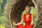 Attractive and happy 40s or 50s middle aged Asian woman in classy and beautiful red dress practicing yoga relaxation and