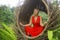 Attractive and happy 40s or 50s middle aged Asian woman in classy and beautiful red dress practicing yoga relaxation and