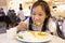 Attractive happy girl sitting and eating dessert,Close up portrait of a hungry greedy girl eating panckaces in the restaurant