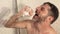 Attractive and happy man with beard dancing and singing in the shower carefree and crazy at home bathroom