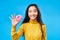 Attractive happy woman holding tasty donut over blue background