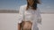 Attractive happy woman in light casual summer clothes posing, walking towards camera at hot salt desert lake in Utah.