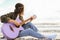 Attractive hippie girl playing an acoustic guitar on the beach