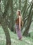 Attractive hippie girl standing among the trees in the forest