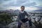 Attractive hipster with a beard is sitting on a rock high over Athens City with Acropolis view at sunset