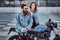 Attractive hipster couple - bearded brutal male in sunglasses and jeans jacket sitting on a retro motorcycle and his