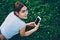 .Attractive hipster girl with braid resting on grass while checking mail on smartphone