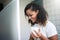 Attractive Hispanic Woman in white shirt smiling and using laptop computer while sitting at home. Young Beautiful Female Mixed