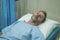 Attractive injured man lying on hospital bed receiving treatment feeling sick and unwell after suffering accident or serious