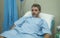 Attractive injured man lying on hospital bed receiving treatment feeling sick and unwell after suffering accident or serious