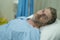 Attractive injured man lying on hospital bed receiving treatment feeling sick and unwell after suffering accident or serious