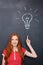 Attractive inspired woman pointing up and having idea over blackboard