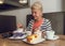 Attractive, joyful older woman drinking coffee while sitting at a cafe. Portrait of mature woman in a cafeteria.