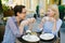 Attractive ladies friends chatting in outdoor cafe holding coffee cups smiling