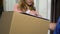 Attractive lady accepting parcel in cardboard box and signing documents delivery