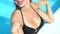 Attractive lady in black bikini stroking breast, sunbathing in swimming pool