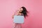 Attractive lady with bright snow-white smile plays hair on pink background. Shot of European tanned