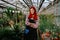 Attractive lady gardener in his own flower greenhouse smiling large looking straight to the camera smiling large