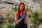 Attractive lady gardener in his own flower greenhouse smiling large looking straight to the camera smiling large