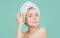 Attractive lady moisturizing face with oil. Beautiful girl with a towel on head, facial treatment, cosmetology, beauty