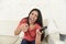 Attractive latin woman at home sofa couch laughing and smiling happy watching television